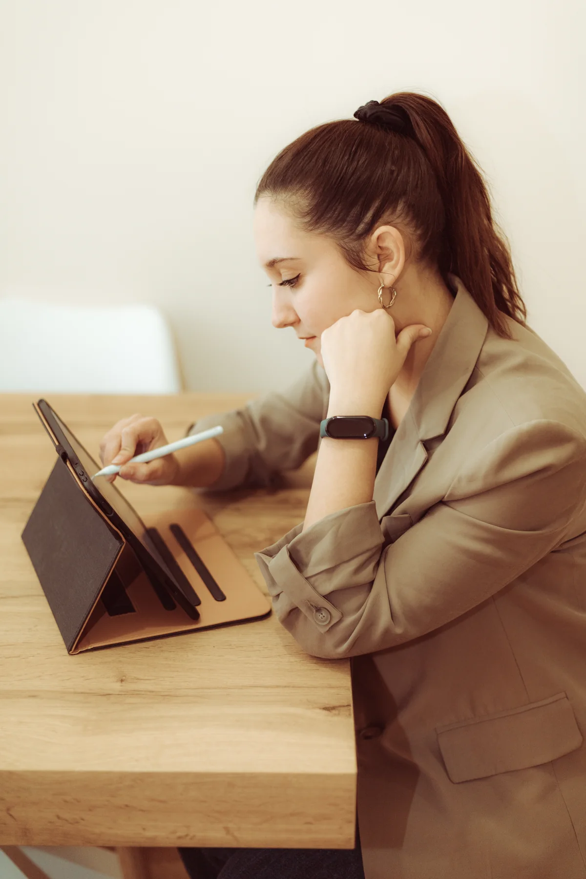 Andrea Gómez Torres, diseñadora UX/UI, dibujando en una tableta sentada en una mesa de madera